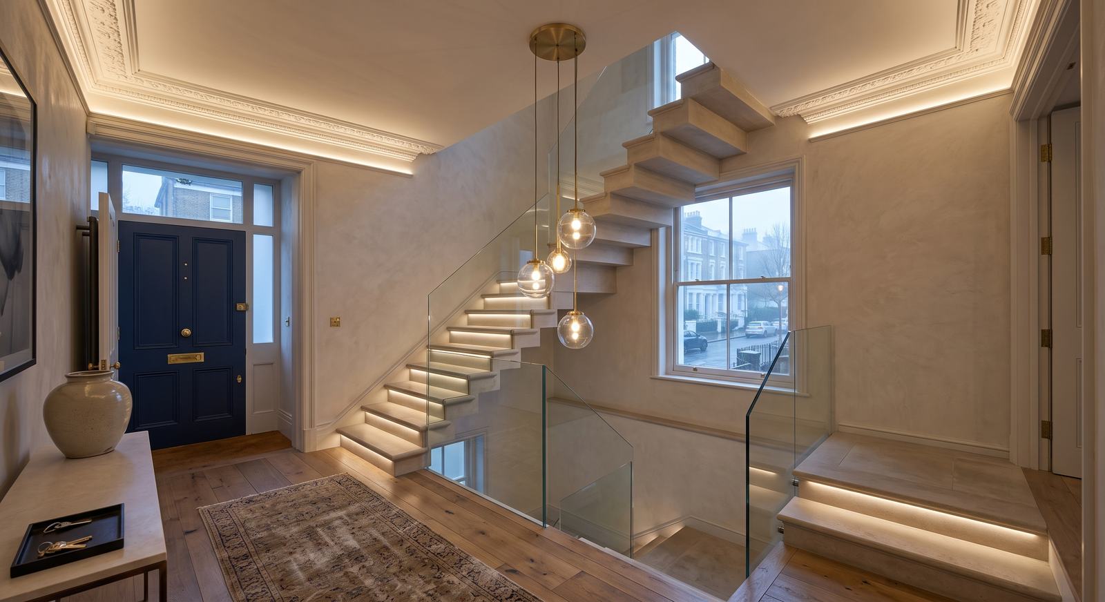 Entrance hall with step-lit stone staircase, cove-lit cornice and brass globe pendants